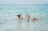 Woman floating in the ocean, reading a book