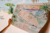 Hands holding a colorful illustrated map of Aruba titled 'Aruba Romance Treasure Map' at Boardwalk Boutique Hotel