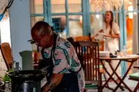 Cook working at an outdoor stove on a porch, warmly lit at night. 