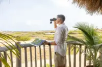 Someone using binoculars in Aruba, featured in the Boardwalk Boutique Hotel Aruba Artist in Residence story.