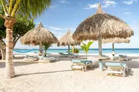 Boardwalk Boutique Hotel Aruba beach area on Palm Beach with palapas and lounge chairs.