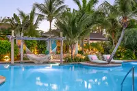 Tropical pool at Boardwalk Boutique Hotel Aruba with palm trees and poolside hammocks.
