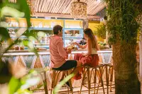Guests toasting during outdoor dining at The Coco Café at Boardwalk Boutique Hotel Aruba.
