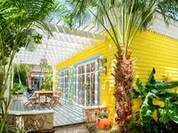Yellow casita exterior with large windows and a private patio, surrounded by palm trees and tropical greenery at Boardwalk Boutique Hotel Aruba.