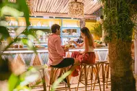 Guests toasting during outdoor dining at The Coco Café at Boardwalk Boutique Hotel Aruba.