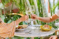 Guests toasting during outdoor dining at The Coco Café at Boardwalk Boutique Hotel Aruba.