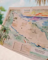 Hands holding a colorful illustrated map of Aruba titled 'Aruba Romance Treasure Map' at Boardwalk Boutique Hotel