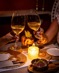 Candlelit dinner at The Coco Café at Boardwalk Boutique Hotel Aruba with wine glasses and evening ambiance.