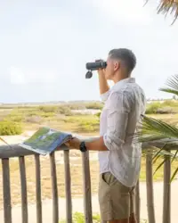 Someone using binoculars in Aruba, featured in the Boardwalk Boutique Hotel Aruba Artist in Residence story.